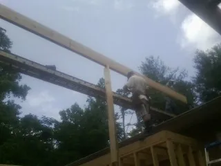Carpenter setting a ridge beam over a new addition frame — Ice Dam Removal by Roofing Brothers in Damon