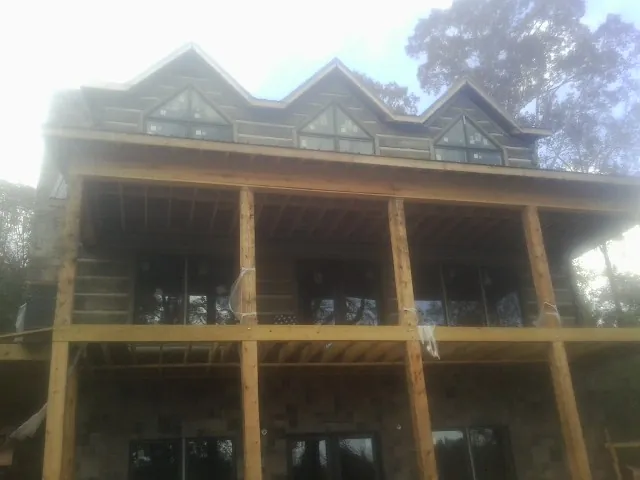 Dormers and porch framing on a large log home under construction — Roof Coating work by our crew in Damon