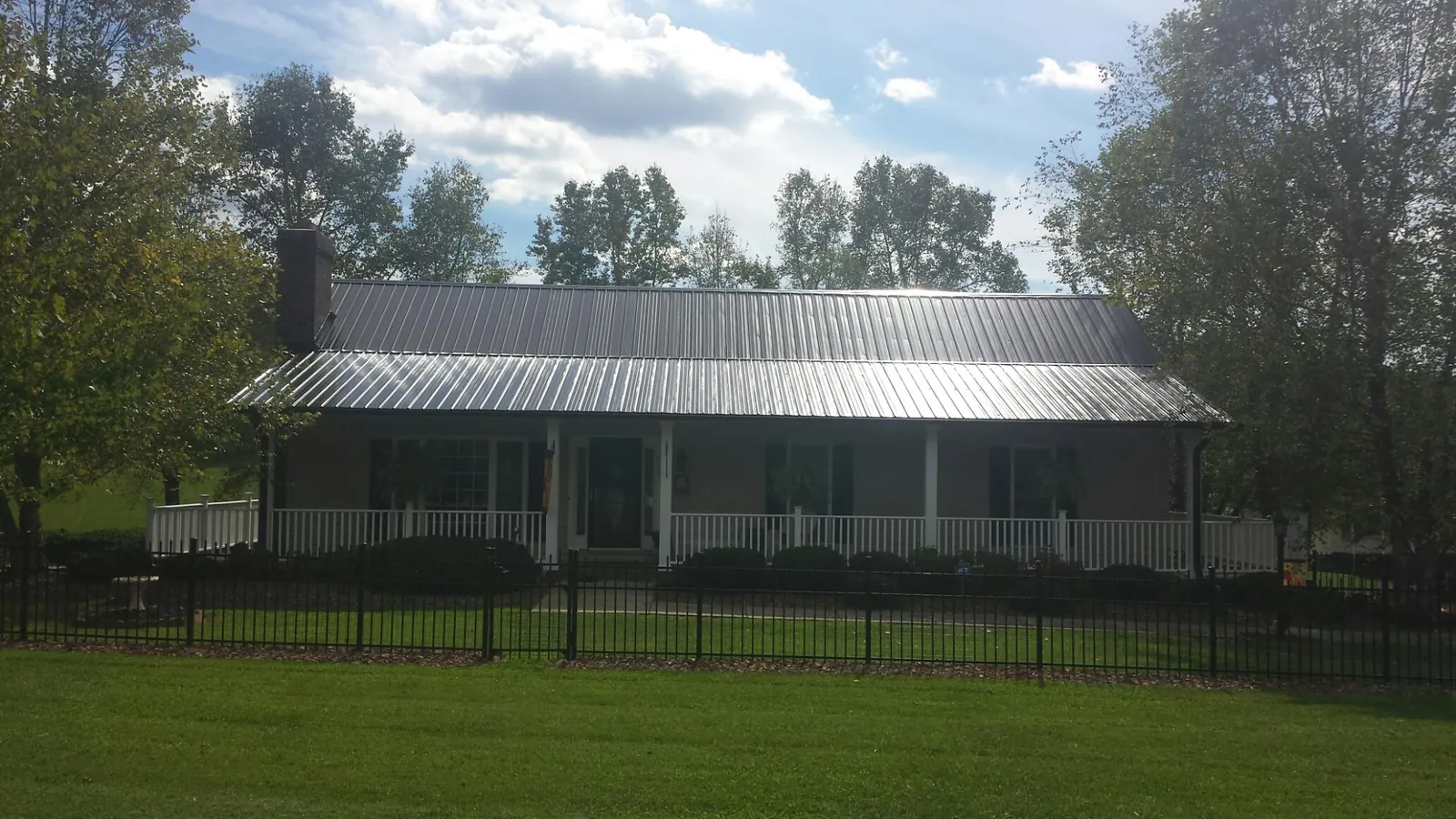 Gray metal roof on a brick ranch with a full width front porch — Gutter Guard Installation work by our crew in Damon