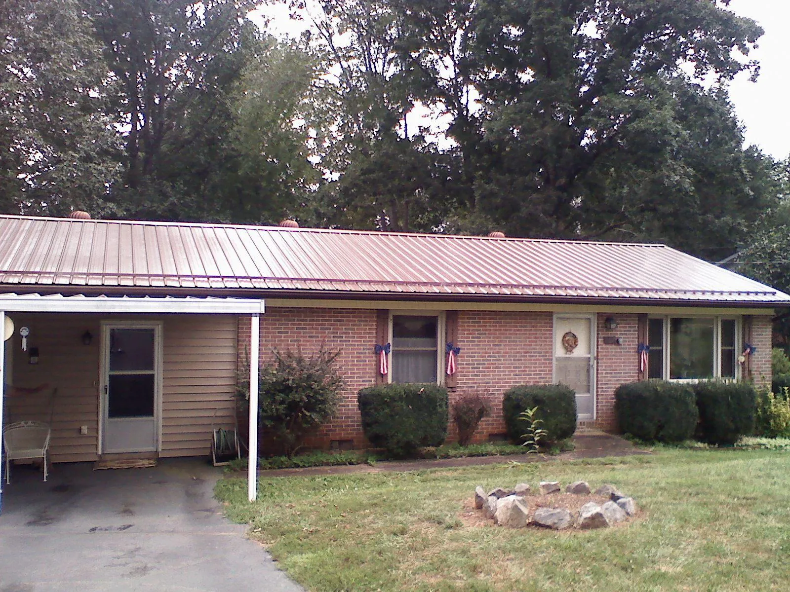 Bronze metal roof and carport on a brick ranch home — Roof Repair work by our crew in Damon
